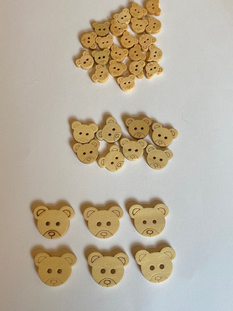 Pode incluir: Uma cole&ccedil;&atilde;o de bot&otilde;es de madeira em forma de urso em v&aacute;rios tamanhos. Os bot&otilde;es s&atilde;o de cor castanho claro e t&ecirc;m um design simples. Existem 28 bot&otilde;es no total.