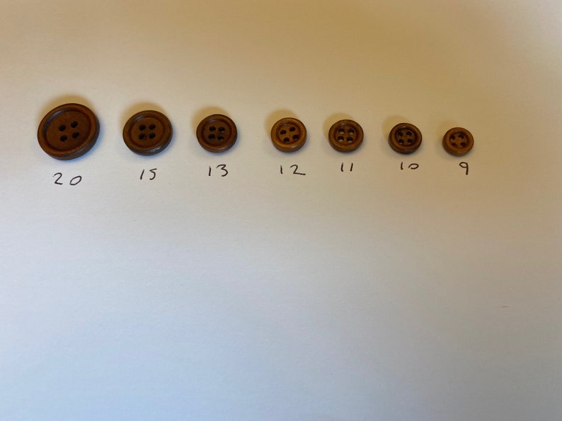 May include: A set of eight brown wooden buttons of varying sizes, labelled with numbers 9 through 20.