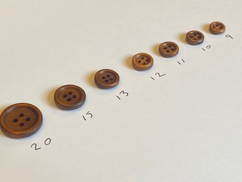 May include: A set of nine brown wooden buttons with four holes each, arranged in a line from smallest to largest. The buttons are labelled with numbers 9 through 20.