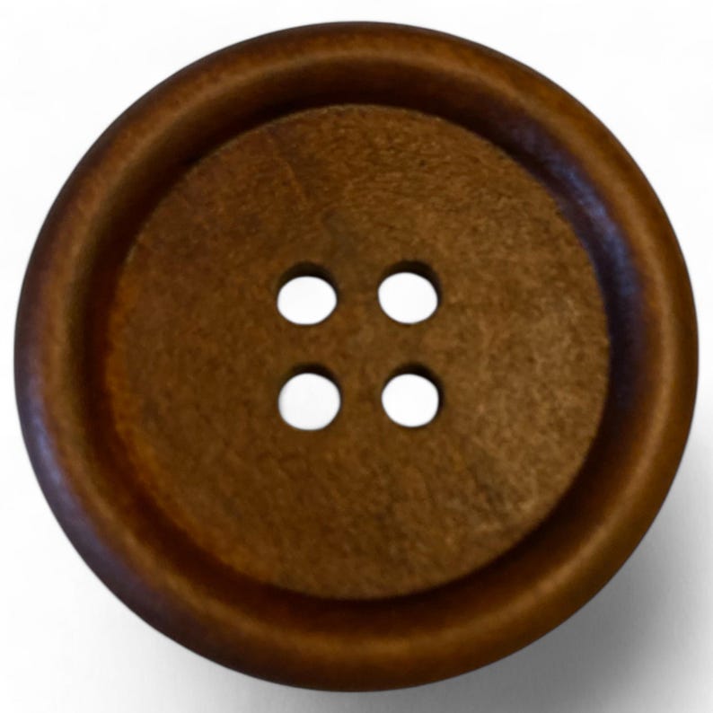 May include: A brown wooden button with four holes. The button has a raised edge and a smooth surface.