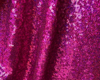 May include: Close-up of a fabric with a pink iridescent sequin pattern. The sequins are small and tightly packed, creating a shimmering effect.
