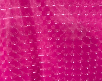 May include: A close-up of a pink, textured, iridescent fabric with a checkered pattern. The fabric has a shiny, reflective surface.
