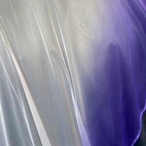 Puede incluir: Tela blanca transparente con un degradado a morado. La tela es suave y fluida, con una textura delicada.
