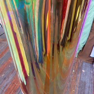 May include: A roll of iridescent holographic vinyl film with a rainbow of colors, including red, orange, yellow, green, blue, and purple. The film is rolled up and has a slight curve to it.
