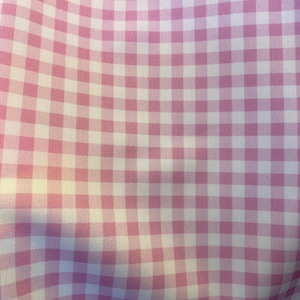 Könnte beinhalten: Rosa-weißes Gingham-Gewebe mit einem dezenten Glanz. Der Stoff ist in einem karierten Muster gewebt.