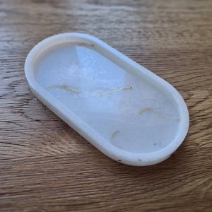 May include: White oval-shaped tray with a smooth, glossy finish. The tray has a subtle marbled effect with thin, gold-coloured lines throughout.