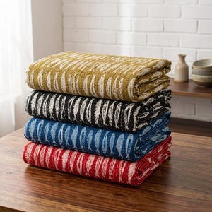 May include: A stack of four folded quilts in various colors. The top quilt is gold with a white pattern, followed by black with white, blue with white, and red with white. Each quilt has a repeating fish design.