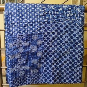 May include: A blue and white kantha quilt with a patchwork design featuring different patterns, including circles, dots, and leaves.