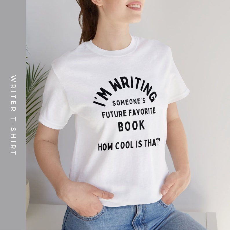 Peut inclure: T-shirt blanc avec un texte noir qui dit "J'&eacute;cris le futur livre pr&eacute;f&eacute;r&eacute; de quelqu'un. C'est cool, non ?"
