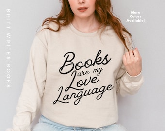 May include: A beige sweatshirt with the text "Books are my love language" in black cursive lettering.