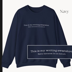 K&ouml;nnte beinhalten: Navyblauer Sweatshirt mit dem Text "This is my writing sweatshirt. Easily distracted. Do not disturb." in wei&szlig; gedruckt.