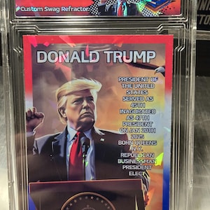 Puede incluir: Una tarjeta coleccionable con un retrato de Donald Trump, el 45&ordm; presidente de los Estados Unidos. La tarjeta tiene un esquema de color rojo, blanco y azul e incluye texto sobre su presidencia y antecedentes.