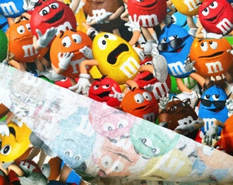 May include: A colorful fabric with a repeating pattern of M&M's candy characters. The characters are in various poses and colors, including red, yellow, blue, green, orange, and brown.