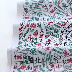 May include: White cotton fabric with a repeating pattern of Mahjong tiles. The tiles are green, red, and black with Chinese characters and symbols. The fabric is perfect for crafting projects, quilting, and home decor.