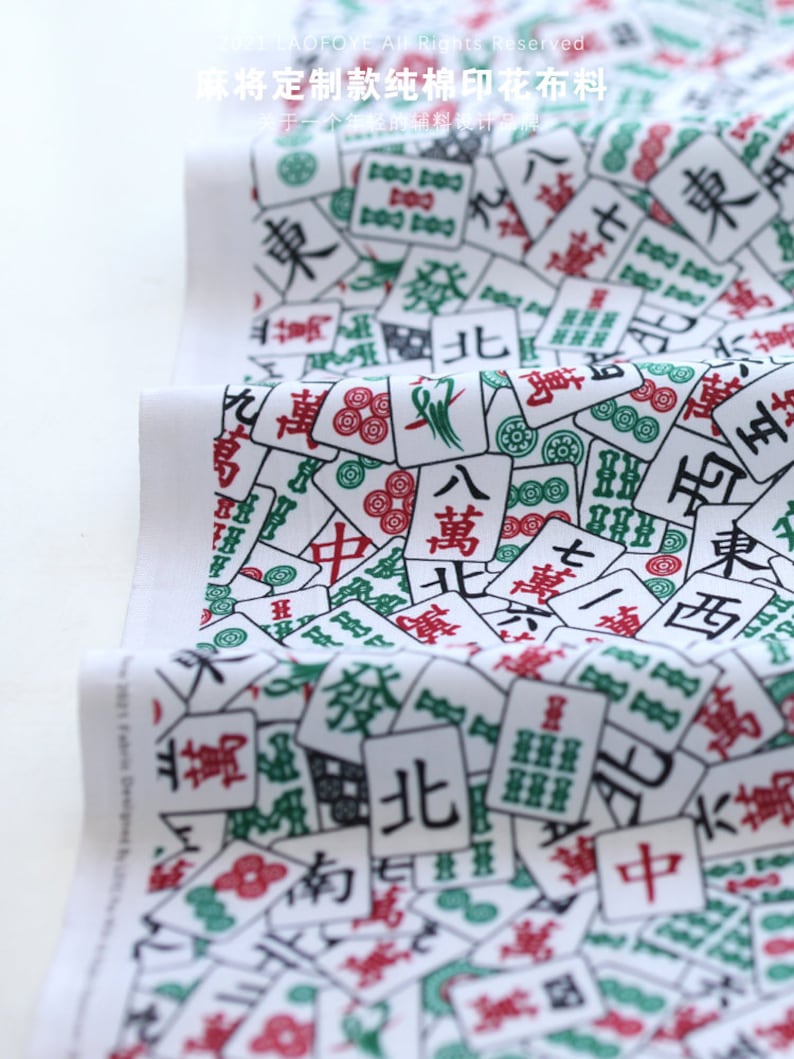 May include: White cotton fabric with a repeating pattern of Mahjong tiles. The tiles are green, red, and black with Chinese characters and symbols. The fabric is perfect for crafting projects, quilting, and home decor.