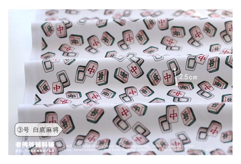 May include: White fabric with a repeating pattern of green and red mahjong tiles. The tiles have Chinese characters on them. The fabric is 2.5 inches wide.