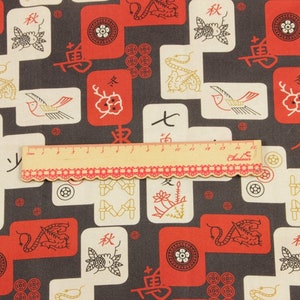 May include: Fabric with a repeating pattern of red and white tiles, each featuring Asian-inspired symbols and illustrations. The background is a dark gray. A ruler with red trim is placed across the fabric.