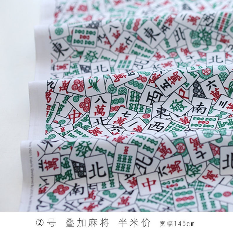 May include: White fabric with a repeating pattern of green and red Chinese mahjong tiles. The tiles feature various Chinese characters and symbols. The fabric is 145 cm wide.