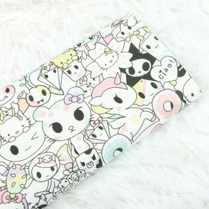 May include: White fabric with a colourful, cartoon-style print featuring various characters, including a unicorn, a skull, and a donut. The text "Ciao!" is included in the print.