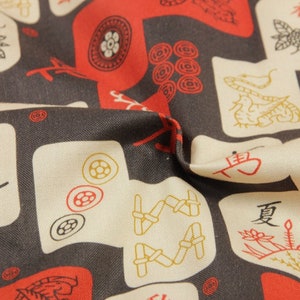 May include: Close-up of fabric with a repeating pattern of red and gold illustrations on a dark gray background. The design includes stylized figures, circles, and Chinese characters on off-white squares.