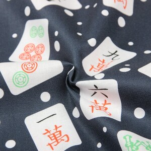 Pu&ograve; includere: Un tessuto blu scuro con uno sfondo bianco a motivi di tessere di mahjong cinesi. Le tessere hanno caratteri cinesi neri e rossi e simboli verdi e rossi.
