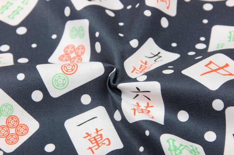 Pu&ograve; includere: Un tessuto blu scuro con uno sfondo bianco a motivi di tessere di mahjong cinesi. Le tessere hanno caratteri cinesi neri e rossi e simboli verdi e rossi.