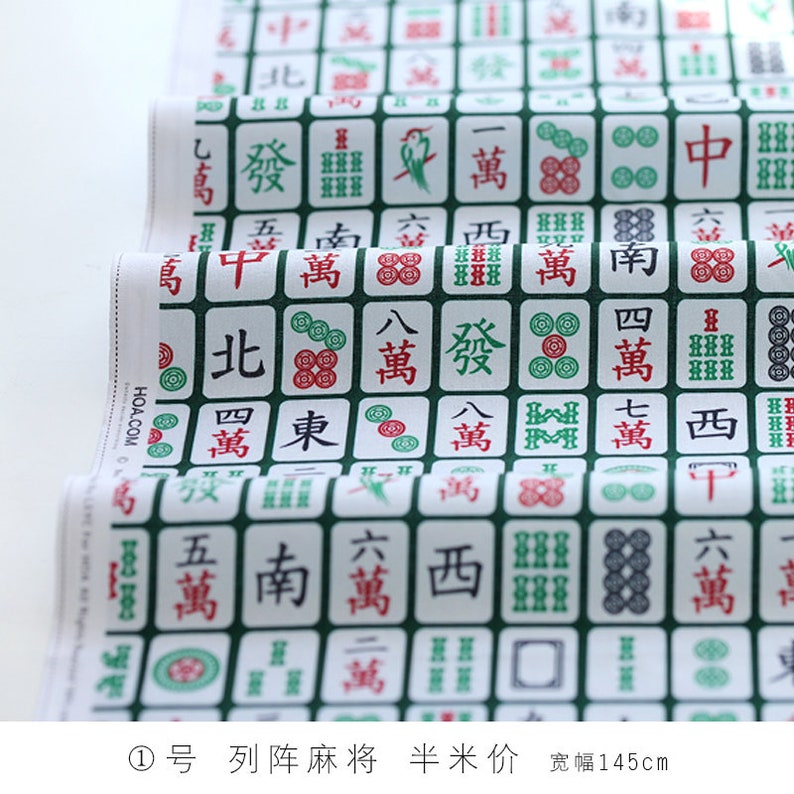 May include: Green and white fabric with a repeating pattern of Chinese mahjong tiles. The tiles feature various Chinese characters and symbols. The fabric is 145 cm wide.