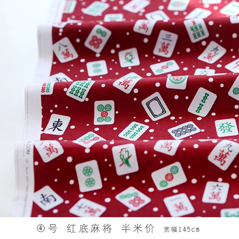 May include: Red fabric with a white background featuring a repeating pattern of mahjong tiles. The tiles have Chinese characters and symbols in green and black. The fabric has small white dots scattered throughout.