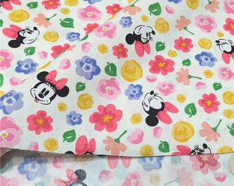 May include: White cotton fabric with a repeating pattern of pink, yellow, and purple flowers and cartoon mouse faces.