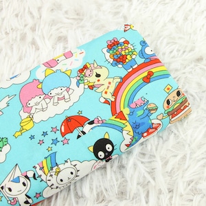 May include: A blue fabric with a colourful pattern of cartoon characters, rainbows, and stars. The characters include a unicorn, a cat, a monster, and a hamburger.