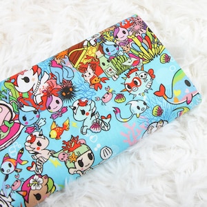 May include: Blue fabric featuring a colourful, whimsical pattern of cartoon sea creatures, including fish, seahorses, and a crab. The fabric is ideal for crafting projects, such as making bags, cushions, or clothing.