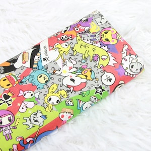 May include: A colourful fabric featuring a repeating pattern of cartoon characters, including a unicorn, a dinosaur, a skull, and a bunny. The fabric is printed in a variety of colours, including pink, blue, green, yellow, and red. The fabric is made of cotton and is suitable for a range of sewing projects.