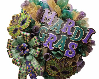 Corona de Mardi Gras con letrero metálico y máscaras decorativas