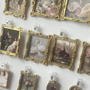 Peut inclure: Un tableau blanc avec une variété de miniatures encadrées dans des cadres dorés. Les cadres sont disposés en rangées et en colonnes. Les images représentent divers sujets, notamment des personnes, des animaux et des fleurs. Le tableau est décoré d'une petite pancarte qui indique "Uptown Mints Est. 2021 Crafting Happiness".