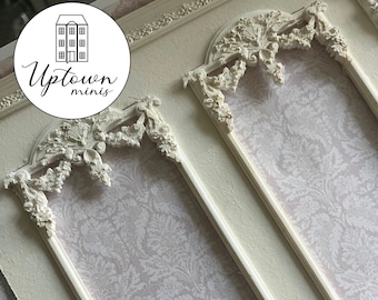 May include: A white painted backdrop with three decorative frames. The frames have ornate details and are set against a pale pink background with a damask pattern. The backdrop is perfect for miniature photography.