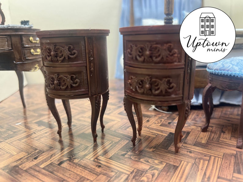 May include: Two brown wooden nightstands with ornate carvings and two drawers each. The nightstands have curved fronts and stand on four legs. The nightstands are on a wood floor.