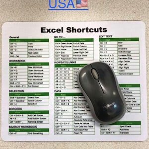 May include: A rectangular mouse pad featuring a white surface with green headers and black text listing various Excel Shortcuts, including sections for General, Workbook, Selection, Borders, Search, Go To, Rows/Columns, Data, and Edit Text, with a grey Logitech mouse.