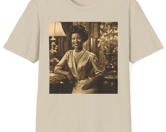 May include: A beige t-shirt with a vintage photograph of a woman in a light-colored dress and a pearl necklace. The woman is sitting in a chair with a lamp behind her.