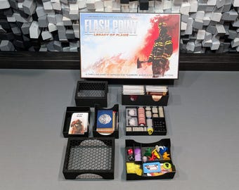 May include: A black and white image of a board game called "Flash Point: Legacy of Flame". The game is a thrilling game of heroism and teamwork, where every second matters. The image shows the game box and several black plastic storage boxes with various game components.