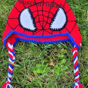 May include: Red, blue, and white crocheted Spider-Man hat with a white eye design and long braided ties.