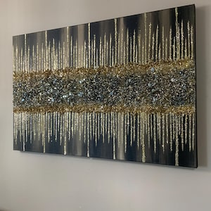 Puede incluir: Una pintura rectangular sobre lienzo con un dise&ntilde;o abstracto texturizado. La pintura presenta un fondo oscuro con l&iacute;neas verticales de purpurina dorada y una banda horizontal de purpurina dorada y plateada.