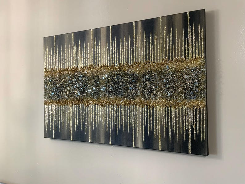 Puede incluir: Pintura abstracta con una superficie texturizada y brillante. La pintura presenta un fondo oscuro con acentos de purpurina dorada y plateada.