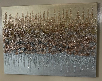 May include: A rectangular canvas painting with a textured, abstract design. The painting features a gradient of silver, gold, and rose gold glitter, creating a shimmering effect.