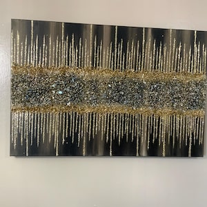 Puede incluir: Pintura abstracta con fondo negro y detalles de purpurina dorada y plateada. La purpurina est&aacute; dispuesta en un patr&oacute;n de goteo.