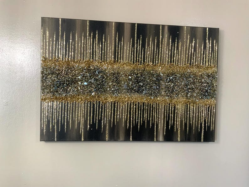 Puede incluir: Pintura abstracta con fondo negro y detalles de purpurina dorada y plateada. La purpurina est&aacute; dispuesta en un patr&oacute;n de goteo.