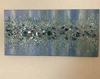 May include: A blue and silver abstract painting with a textured surface. The painting features a band of silver glitter and small, mirrored pieces.