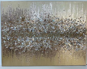 Op de afbeelding: Abstracte wandkunst met een gouden achtergrond en een textuurlaag van iriserende glitter en kleine witte stukjes gebroken schelp.