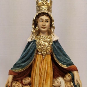 以下が含まれることがあります： 金色の冠と青いローブを着た女性の置物で、腕に人々を抱えています。女性は穏やかな表情をしており、宗教的な人物として描かれています。