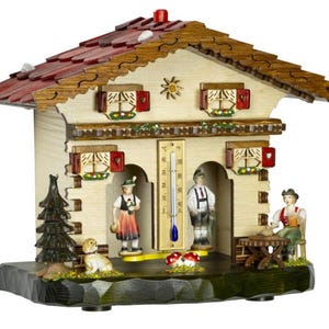 May include: A wooden chalet-style weather station with a red tile roof, decorative trim, and small figures. The chalet features a thermometer, miniature figures in traditional attire, a dog, and a small tree. The overall design is detailed and colorful.