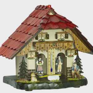 May include: A wooden weather house with a red shingled roof, featuring miniature figures of people and a dog. The house has a thermometer and decorative details, including carved trim and small evergreen trees. The base is dark green.
